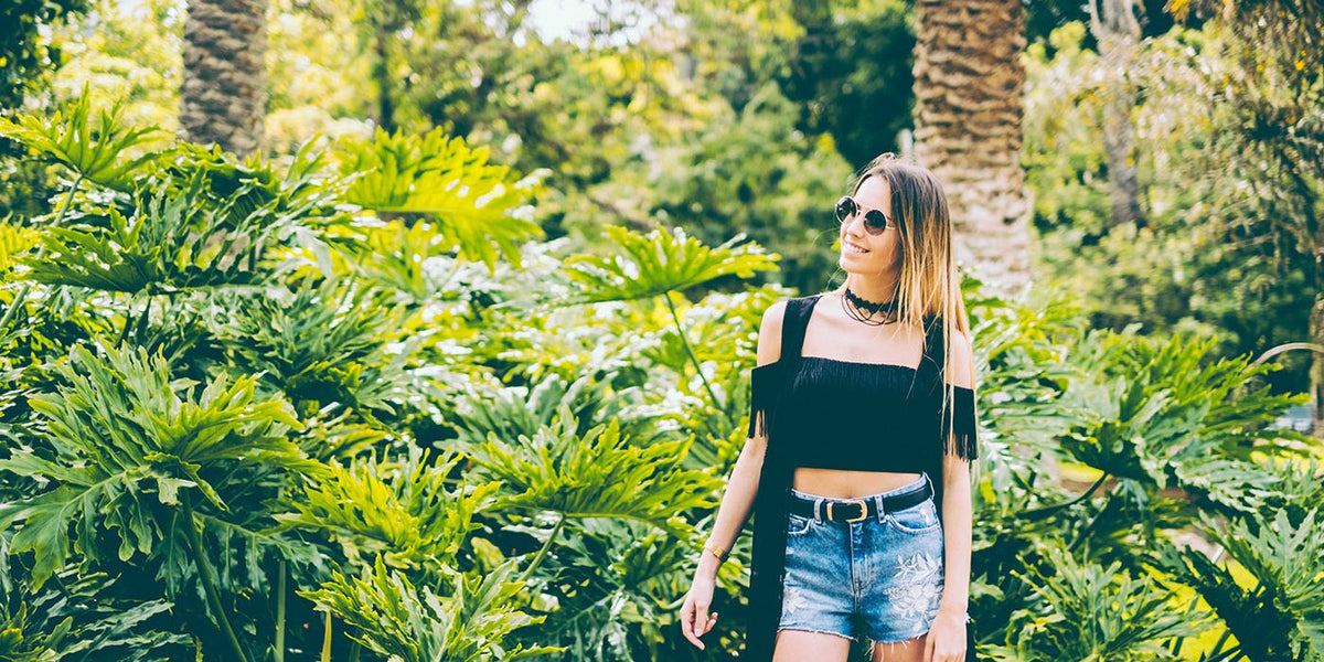 Woman wearing round metal Sunpers sunglasses in a tropical garden